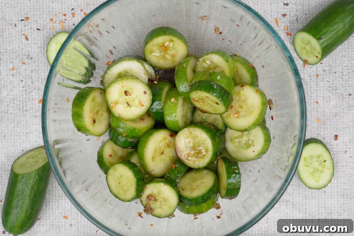 Din Tai Fung-Style Cucumber Salad Recipe That Pops 6 Cucumber slices and dressing mixed in a bowl.