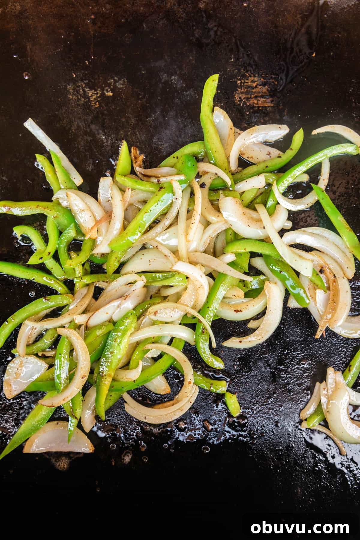 How to Make an Authentic Philly Cheesesteak on a Blackstone Griddle 5 Thinly sliced onion and green pepper sautéing on the Blackstone