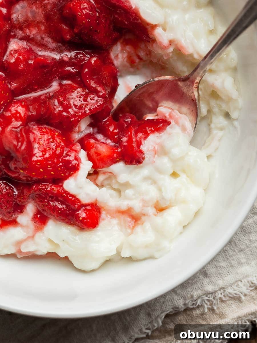 gluten free reis pudding (milchreis) in a bowl topped with roasted strawberries