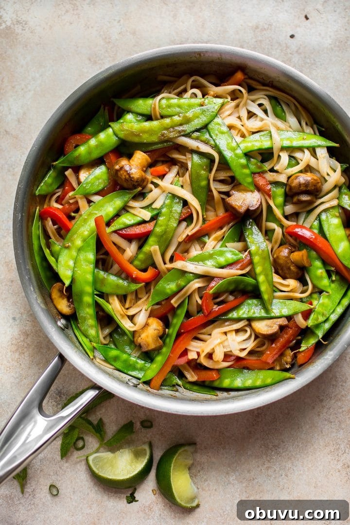Flavorful Vegan Rice Noodle Recipes for Every Meal 3 skillet full of vegan rice noodles with a sweet and spicy ginger garlic sauce and lime wedges