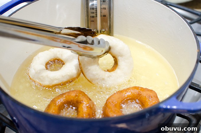 tongs grabbing donuts in hot oil
