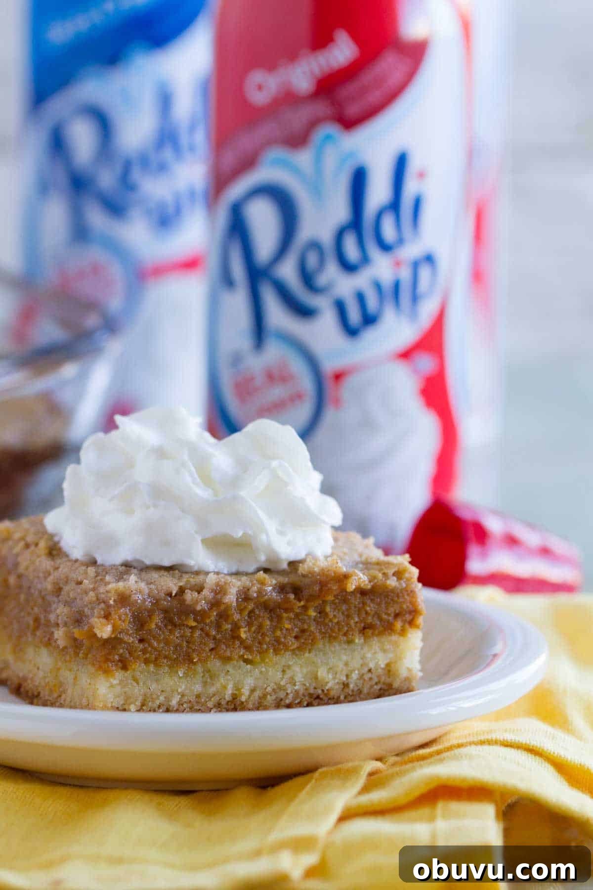 Decadent Pumpkin Pie Layer Cake Recipe 4 Slice of pumpkin pie cake on a plate that is on a yellow towel.