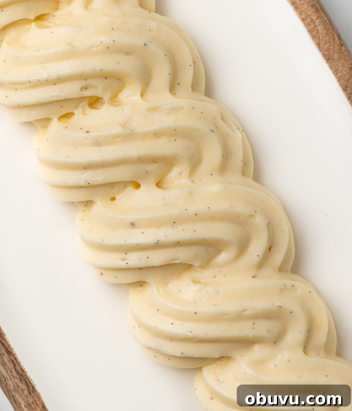 Swirls of cream in a line piped over a white tray - seen from above.