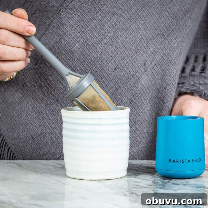 Brew It Stick Review — Is This the Ultimate Camping Coffee Maker? 8 womans hands placing a brew it stick coffee maker into a handmade mug on a marble surface