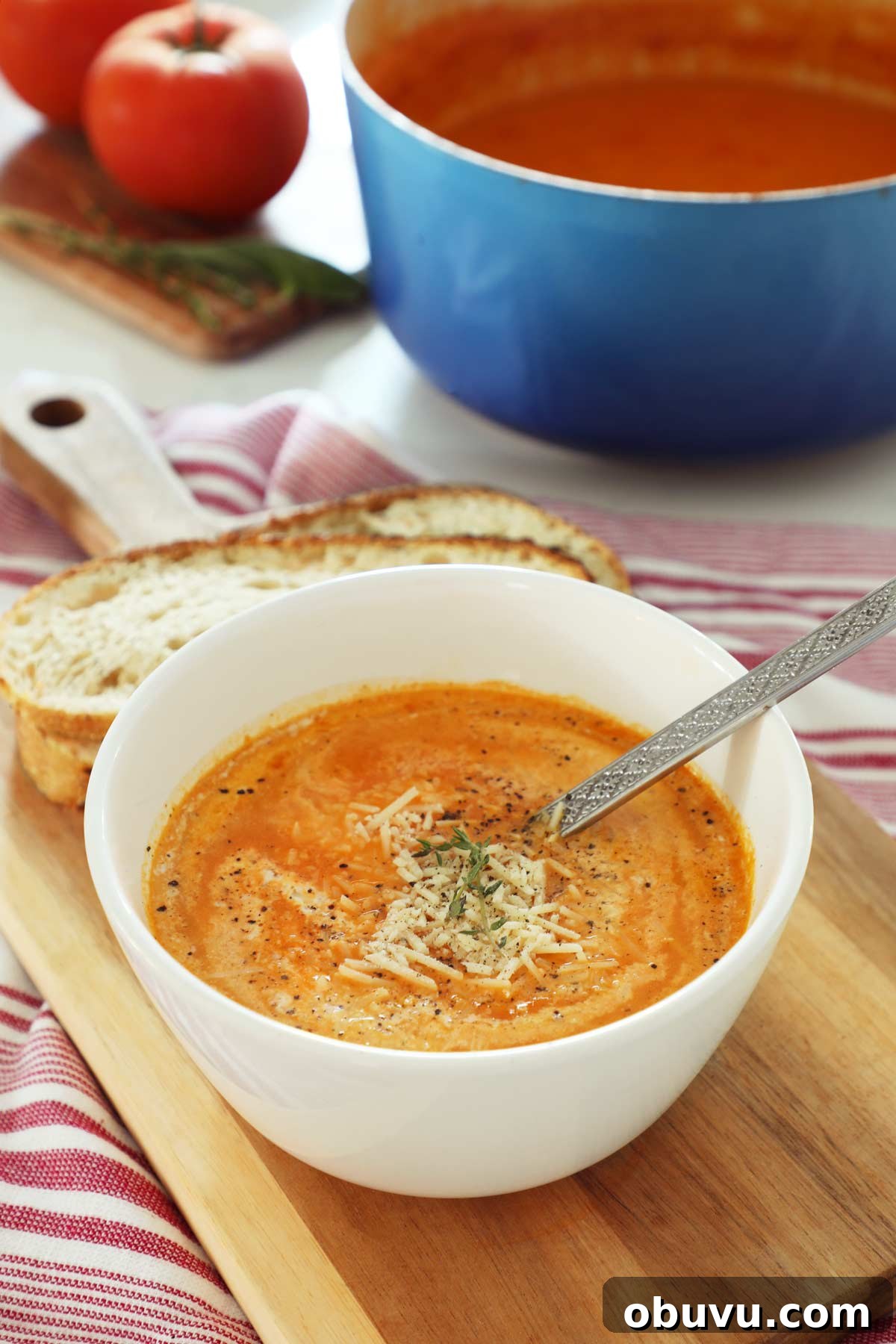 Roasted Red Pepper and Tomato Soup Recipe — Cozy Weeknight Dinner 8 A white bowl on a cutting board filled with tomato and roasted red pepper soup.