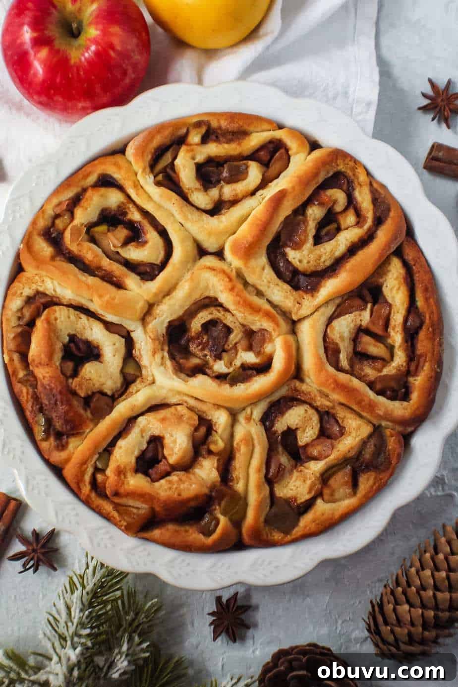 Apple Cinnamon Rolls with Chai-Spiced Cream Cheese Glaze 5 apple cinnamon rolls in a white pie dish before frosting.