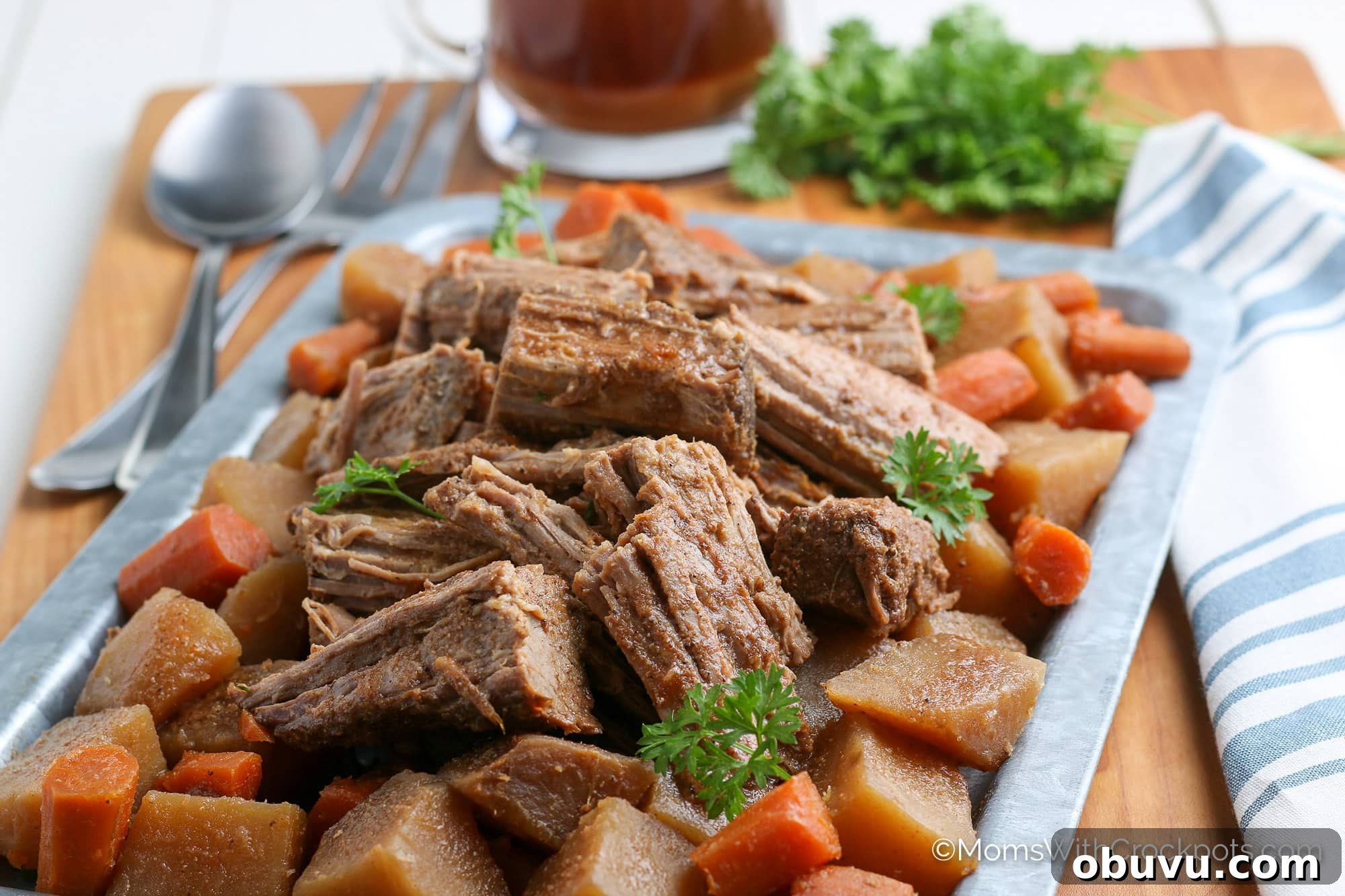 Tender Slow-Cooker Beef Roast with Garlic and Herbs 2 Crock pot beef roast on plate with veggies and au jus in background