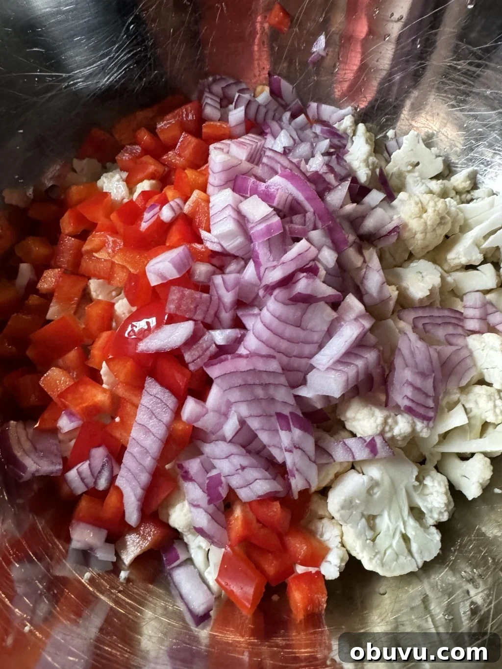 Cauliflower Crunch Salad with Honey Jalapeño Dressing Recipe 5 A mix of chopped red bell pepper, onions, and cauliflower in a metal bowl