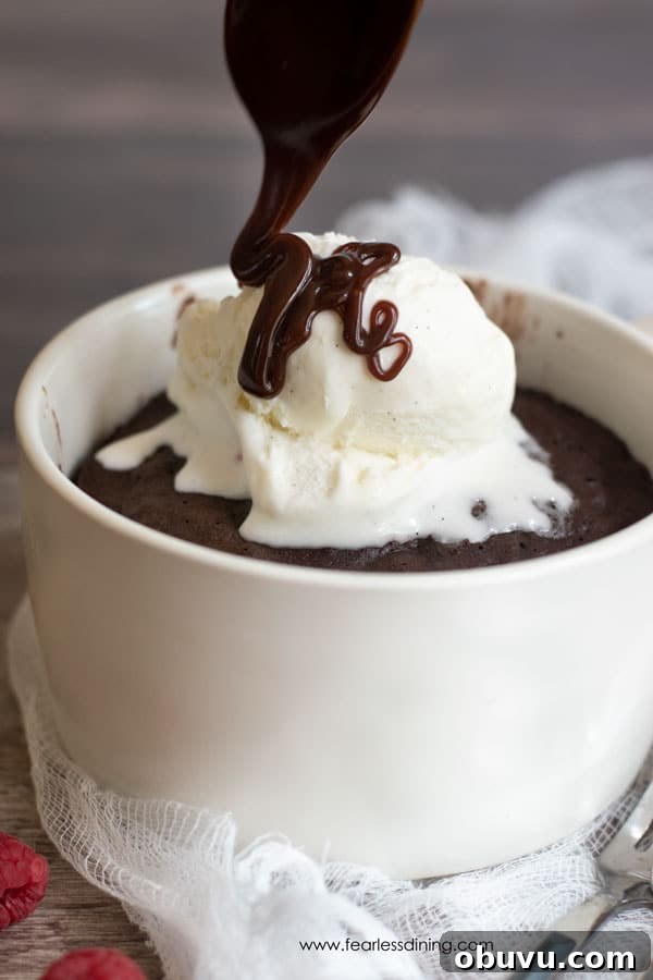 Drizzling hot fudge over the chocolate mug cake.
