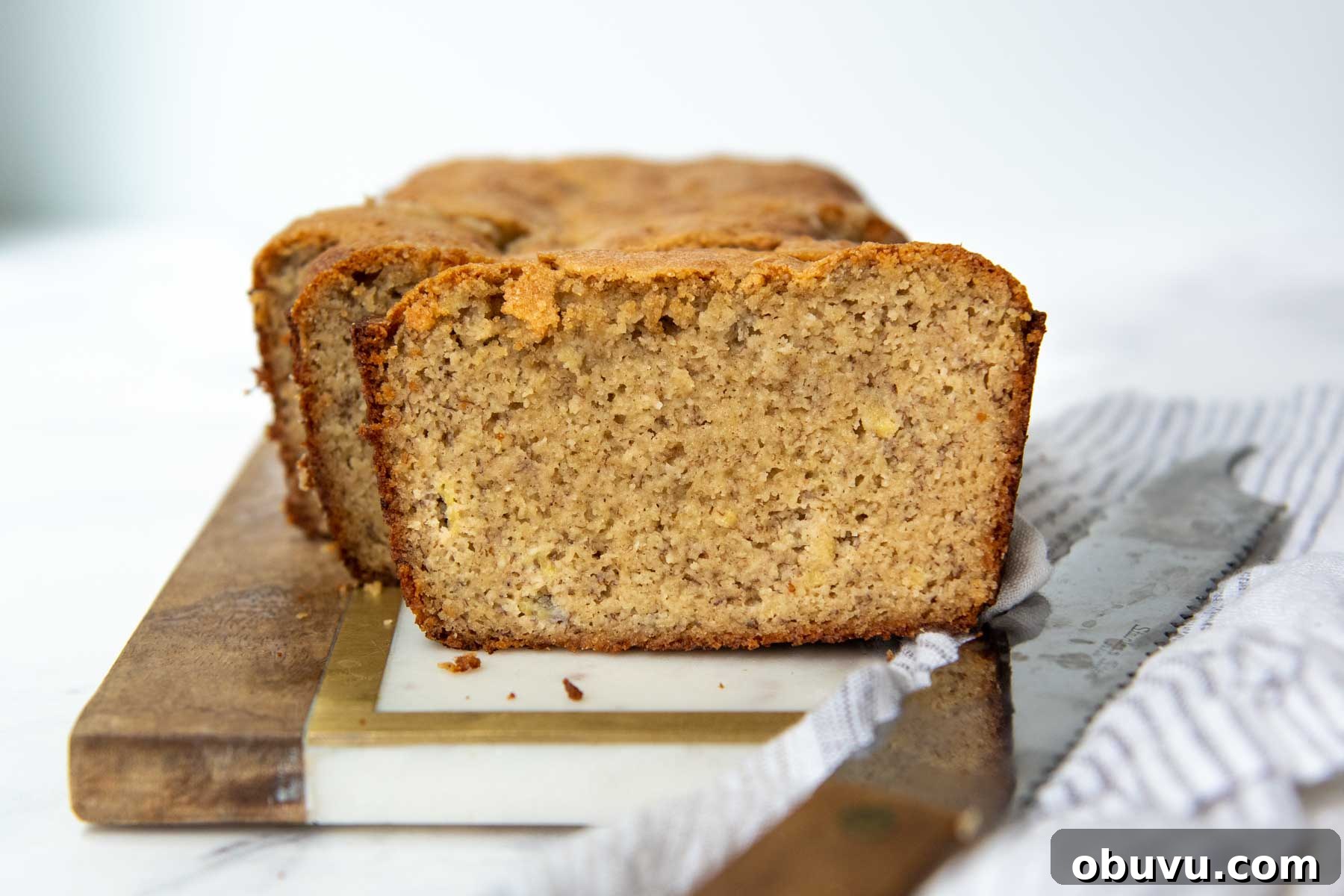 Moist Almond Flour Banana Bread Made with Oil 7 sliced bread on a marble board with a knife resting next to it.