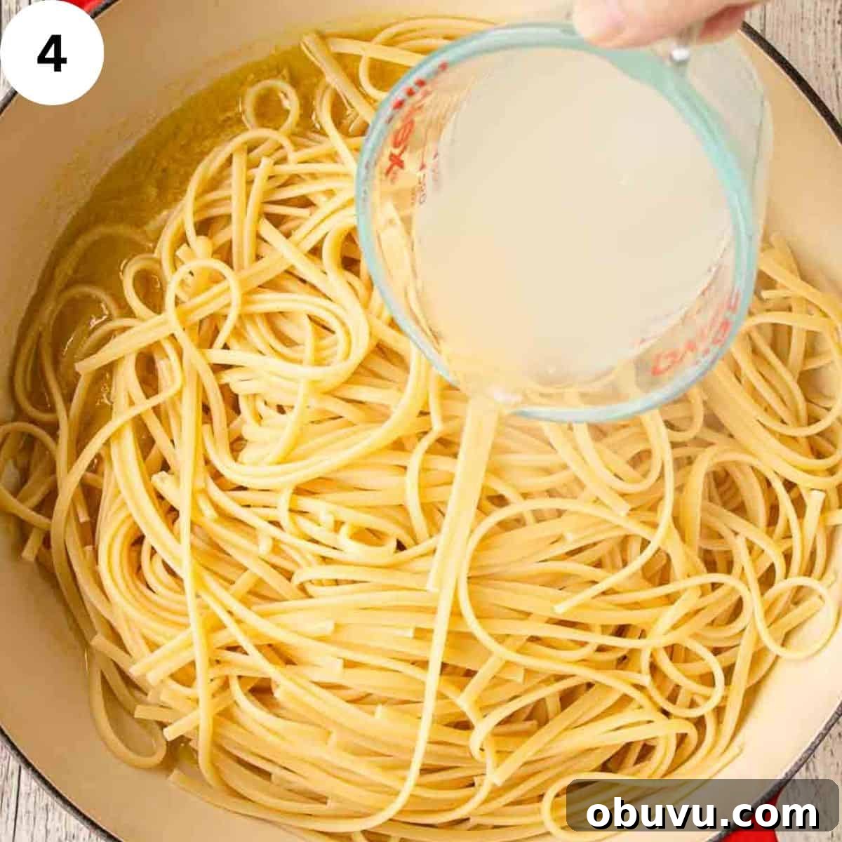 Adding starchy pasta water to a pan of cooked linguine pasta.