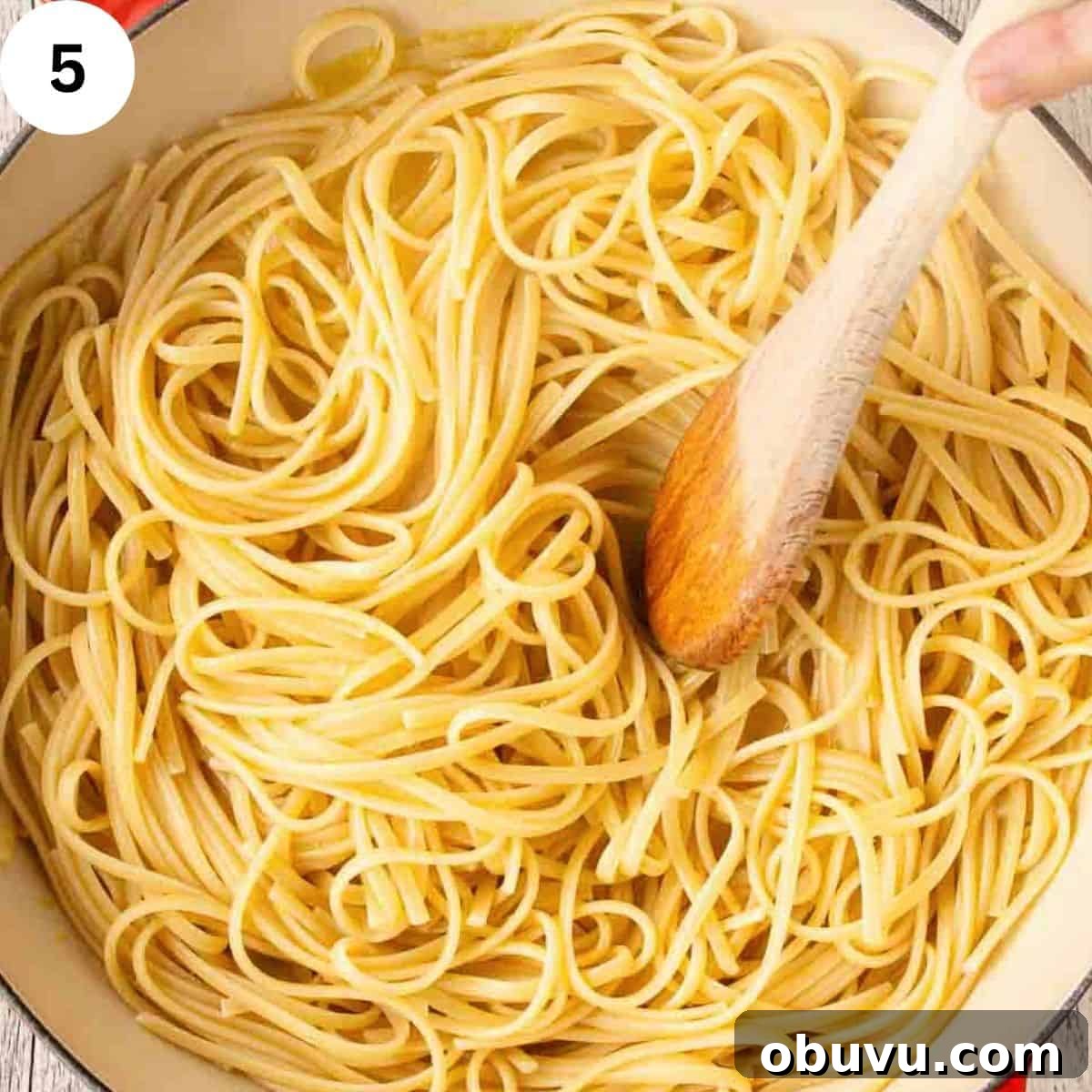 Stirring linguine pasta with a wooden spoon.