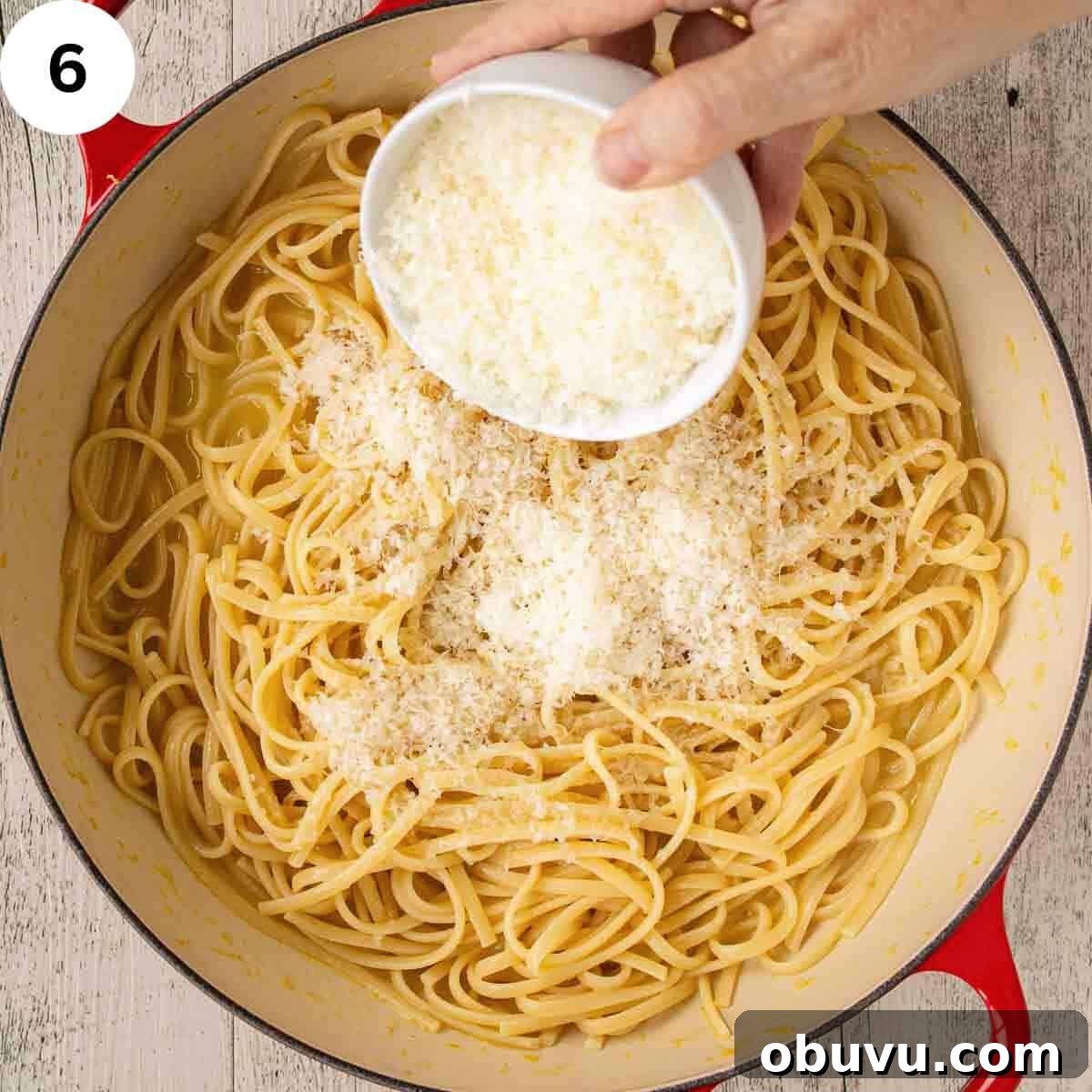 Adding finely grated Parmesan cheese to linguine pasta.