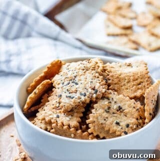 Sourdough crackers in white bowl on wood board.
