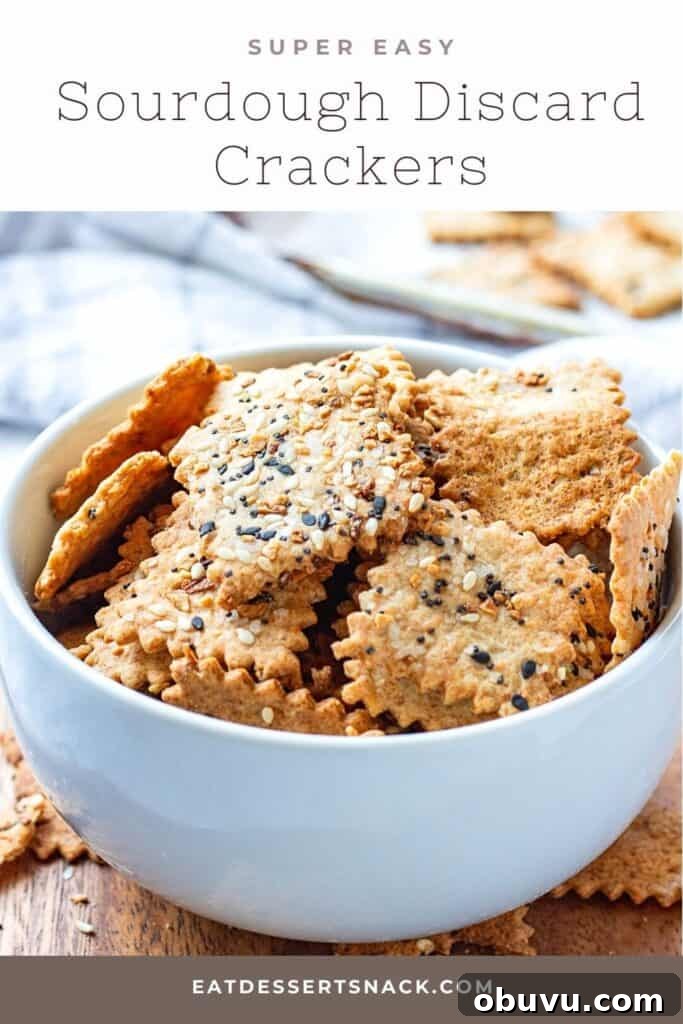 Baked sourdough crackers in white bowl on wood plate.