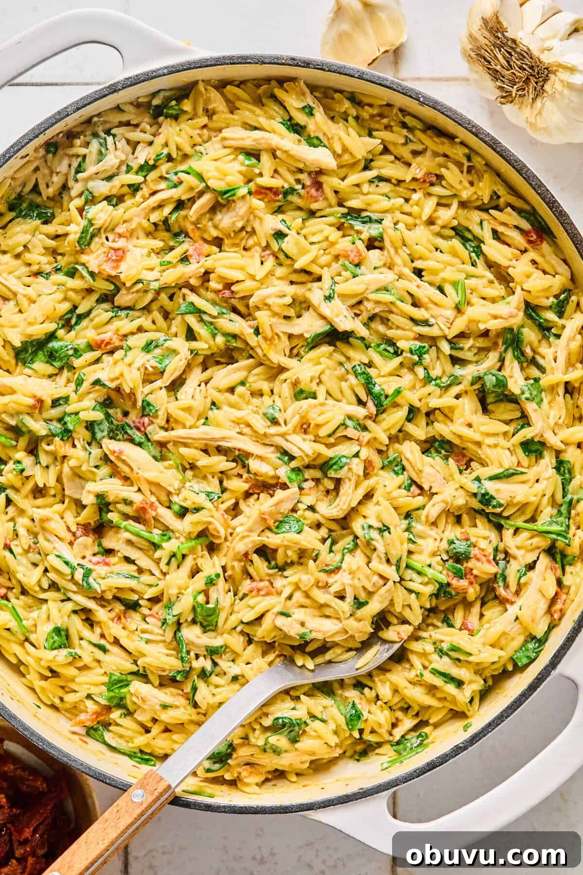 Gluten-Free Marry Me Chicken with Creamy Orzo 7 Marry me chicken orzo garnished with fresh basil and grated parmesan with a serving spoon resting in it.