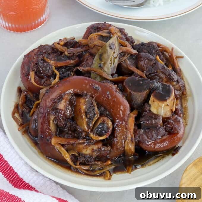 Filipino Pork Hock Paksiw Recipe – Tangy Vinegar Stew 7 paksiw na pata in a white serving bowl with a a plate of steamed rice on the side