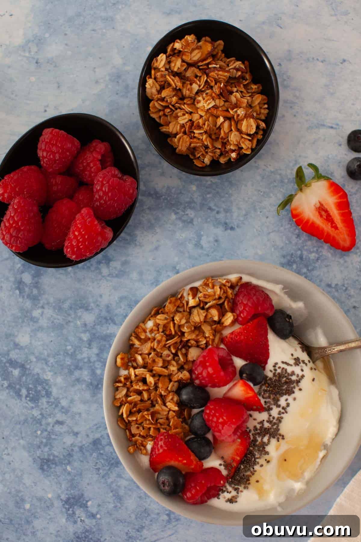 Refreshing Yogurt and Granola Bowl Recipes for Every Morning 8 Three bowls with granola, raspberries, and yogurt topped with granola, berries, chia seeds and honey.