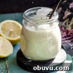 A jar with spicy tahini dressing next to a lemon cut in half