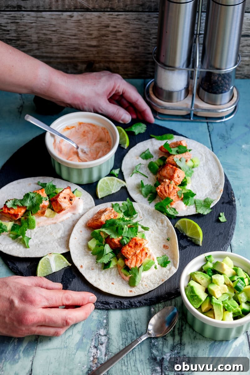 hands putting down a board of tandoori salmon tacos