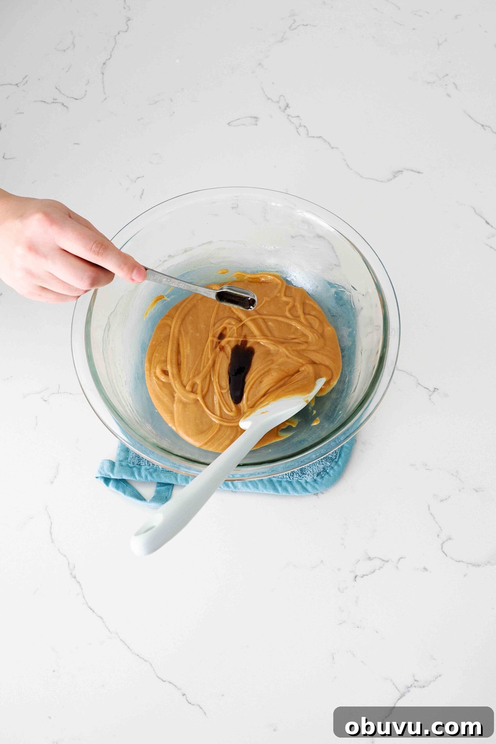 Aunt Deb’s Special K Bars Recipe — Crispy Cereal Treats 5 Vanilla extract is poured into a large glass bowl with a peanut butter mixture.