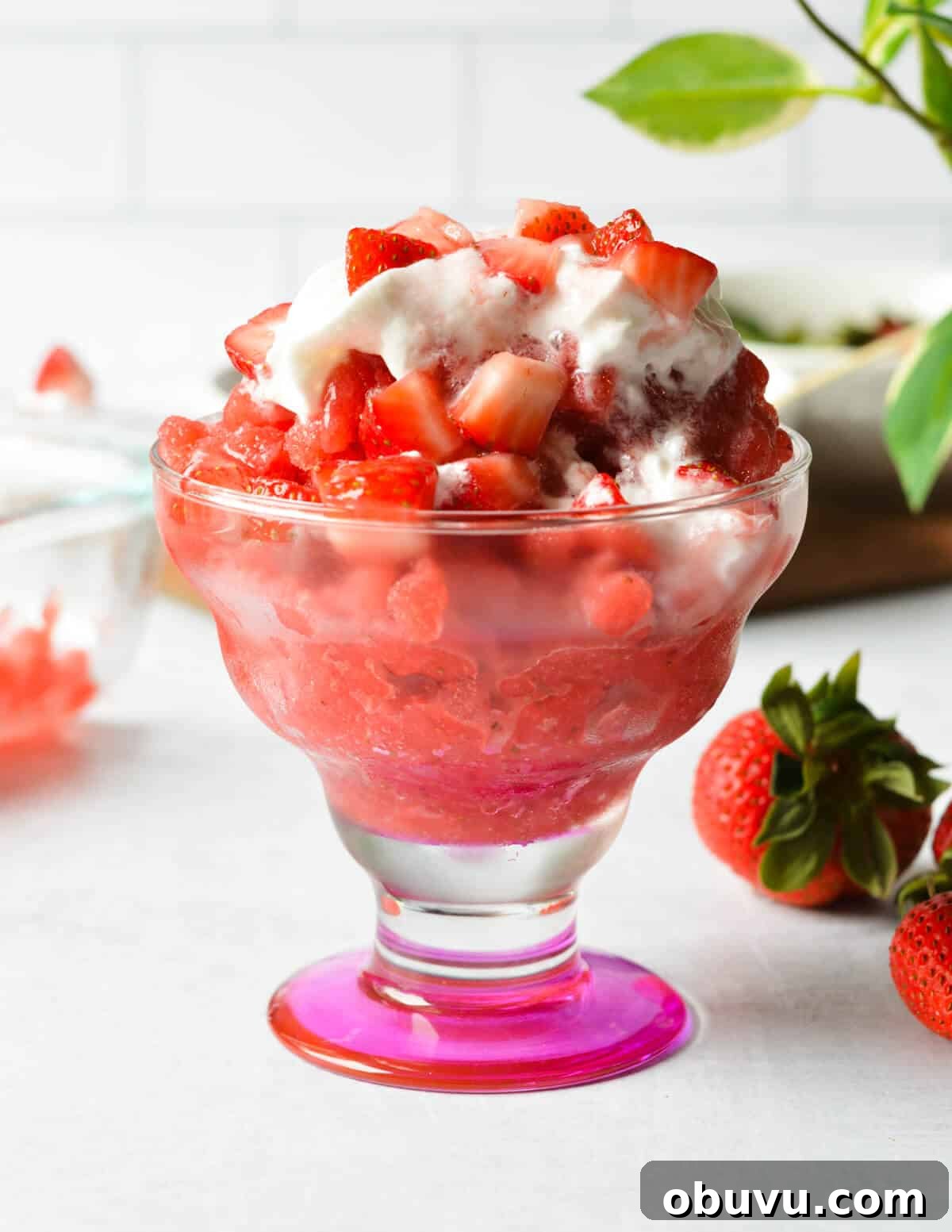 Strawberry & Passion Fruit Granita Recipe for Summer Refreshment 2 a glass cup with strawberry granita, diced strawberries, and whipped cream in it.
