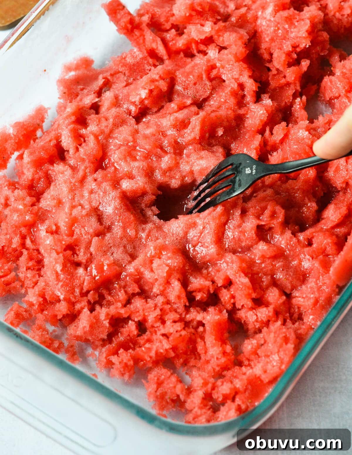 Strawberry & Passion Fruit Granita Recipe for Summer Refreshment 8 fork scraping strawberry granita in a baking dish.