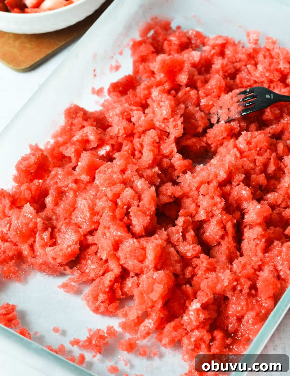Strawberry & Passion Fruit Granita Recipe for Summer Refreshment 9 fork scraping strawberry granita in a baking dish.