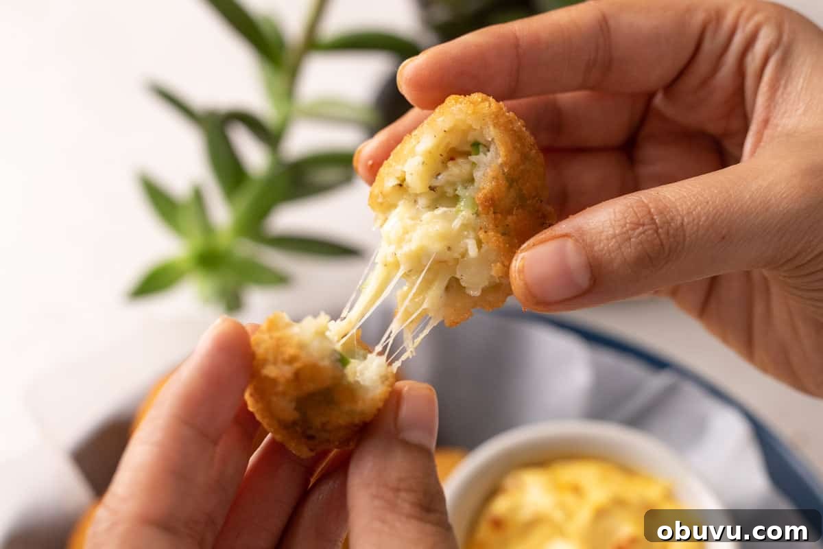 Picture of hands breaking a cheese ball apart to show the cheese pull