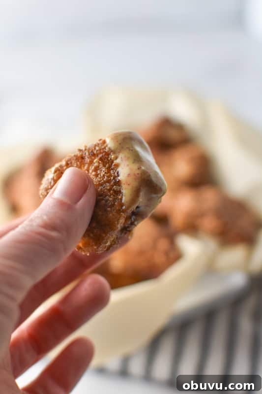 A hand holding a chicken nugget with homemade Chick fil A sauce