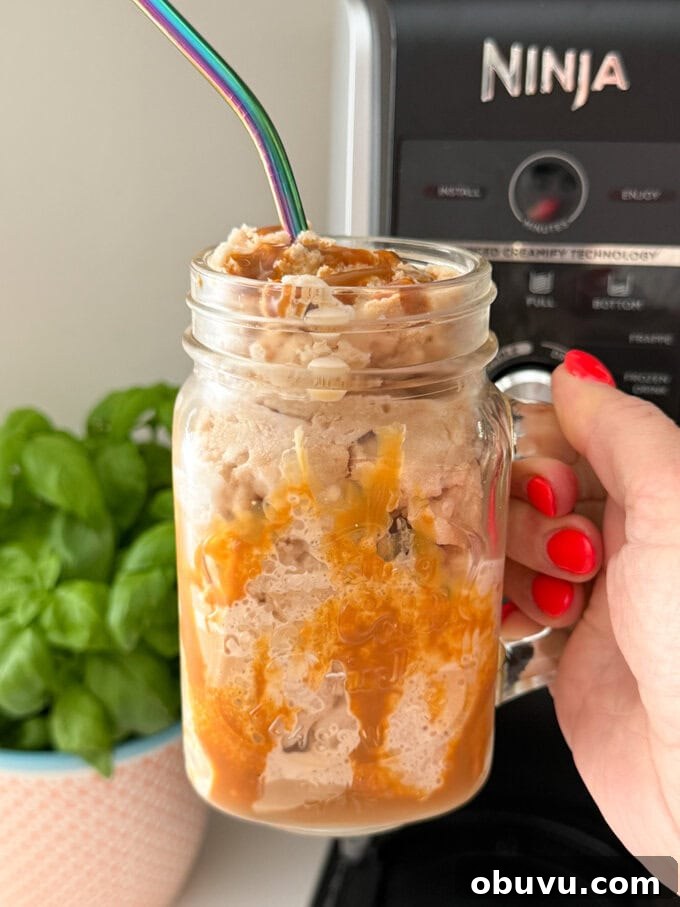 Ninja Creami Coffee Frappe Recipe: Creamy Iced Coffee Dessert 2 Ninja Creami Coffee Frappe served in a Milkshake glass drizzled with caramel sauce and a straw popped in the top.