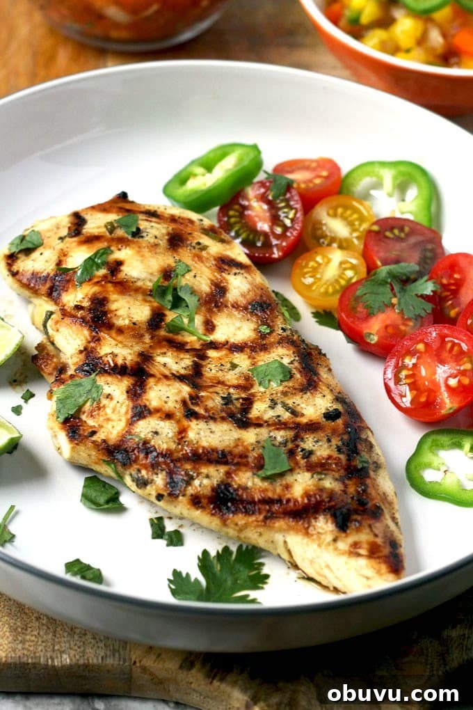 Tequila-Lime Margarita Chicken Recipe with Zesty Marinade 3 Grilled chicken breast half served with tomatoes on a white plate.