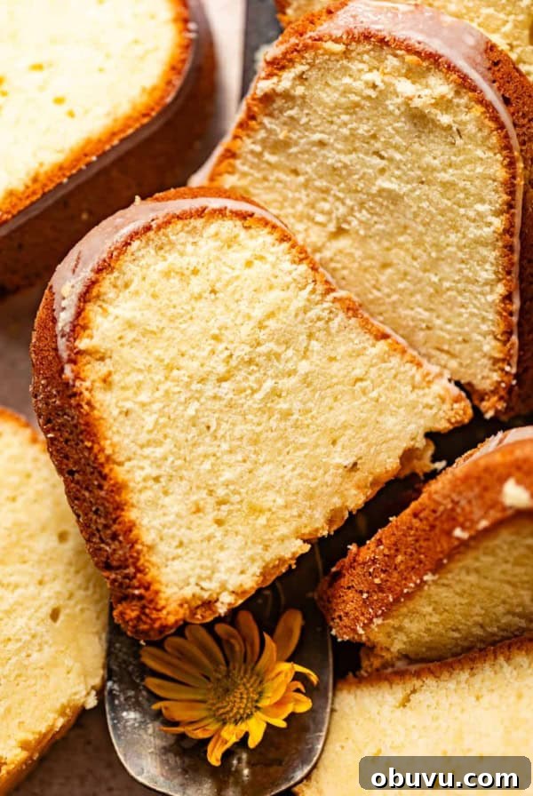 lemon cream cheese pound cake sliced on a serving tray and topped with cream cheese glaze.