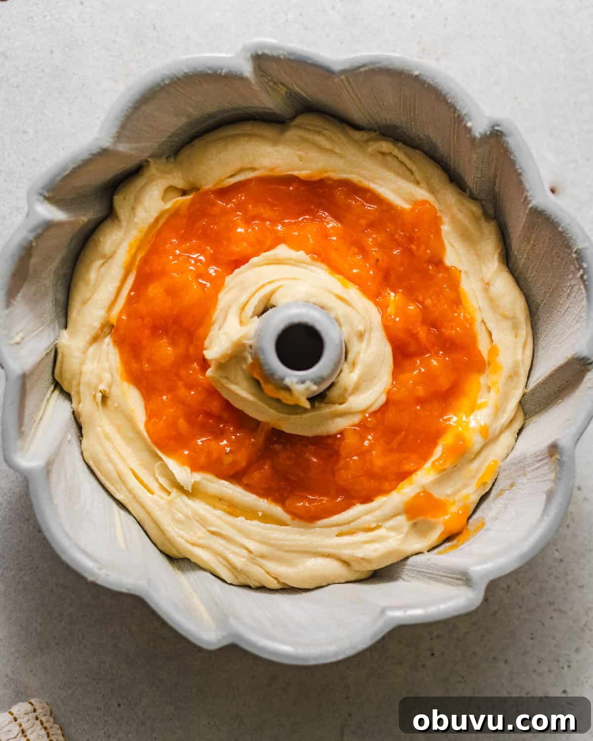 half of the cake batter poured into the bundt pan with the apricot filling in the middle.