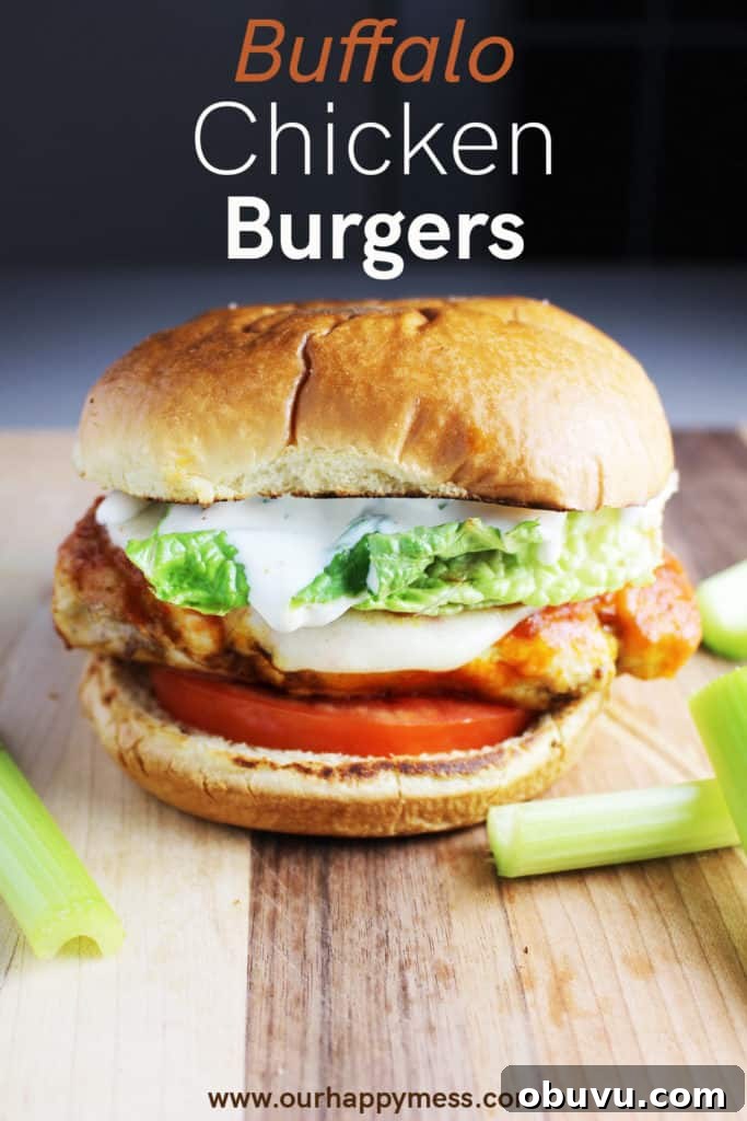 Spicy Buffalo Chicken Breast Burger Recipe 7 A Buffalo chicken burger with cheese, ranch, tomato and lettuce on a wooden cutting board