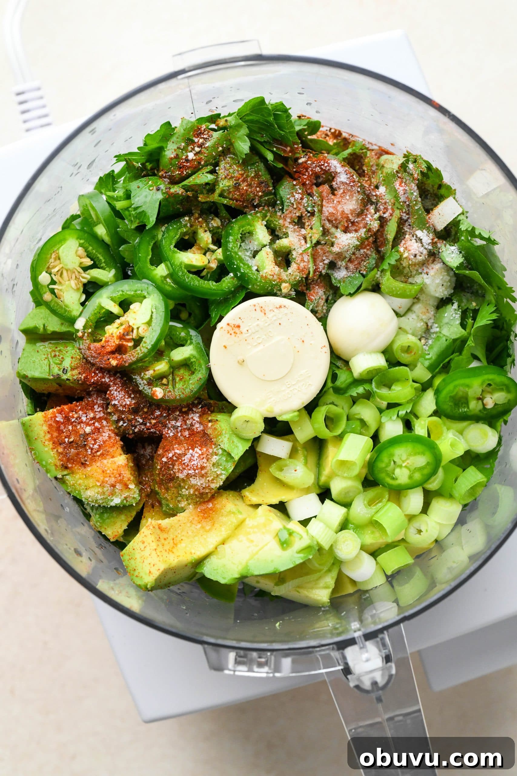 How to make avocado herb green sauce: Ingredients for sauce in the bowl of a food processor.