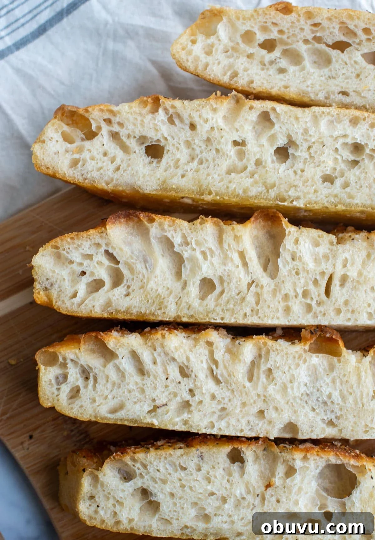 Sourdough Focaccia: Crispy, Airy Italian-Style Loaf Recipe 2 Slices of sourdough focaccia bread are lined up and show airy centers with a golden brown exterior crust.