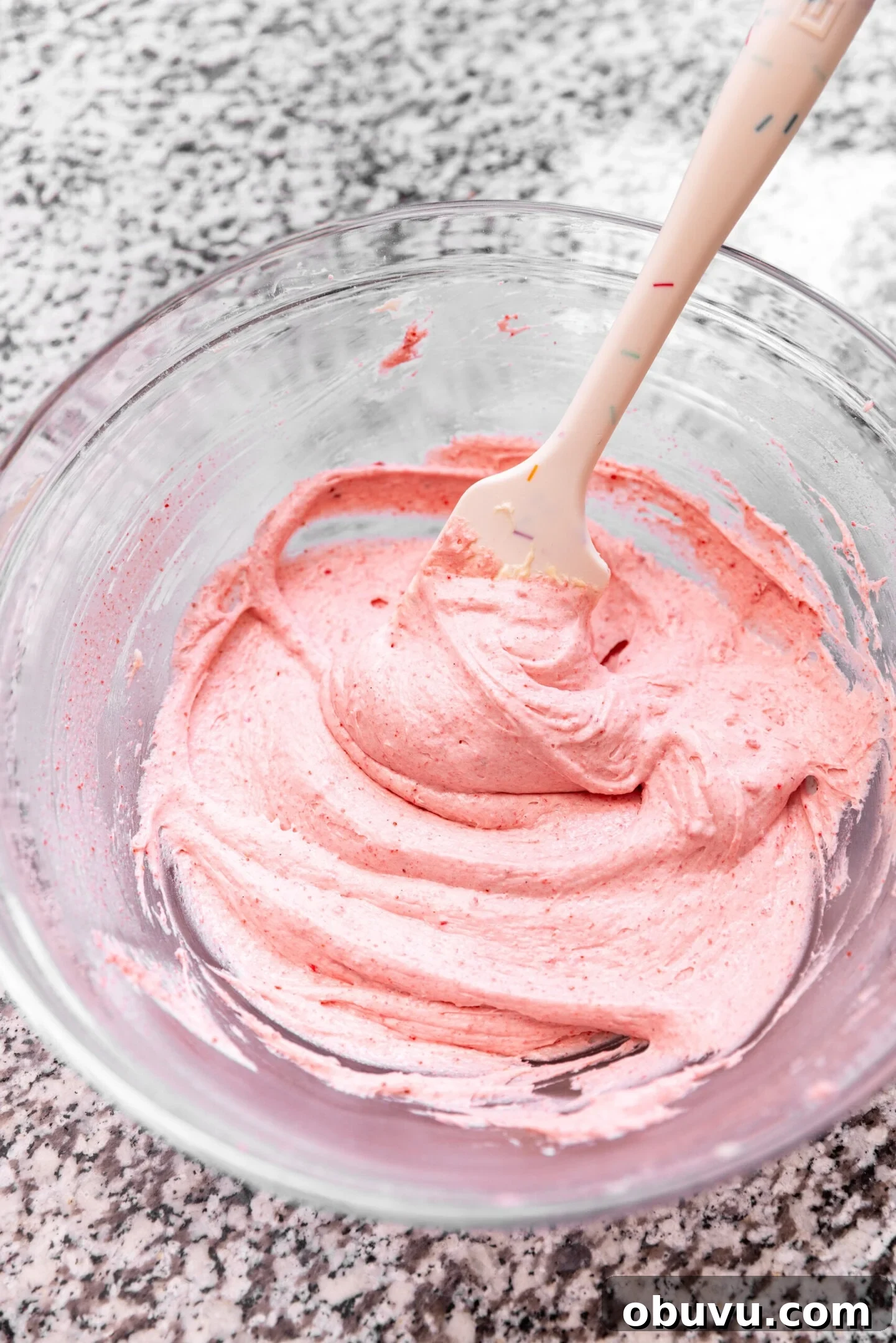 Freeze-Dried Strawberry Cream Cheese Frosting Recipe 3 A bowl of silky smooth strawberry cream cheese frosting with a spatula in it.