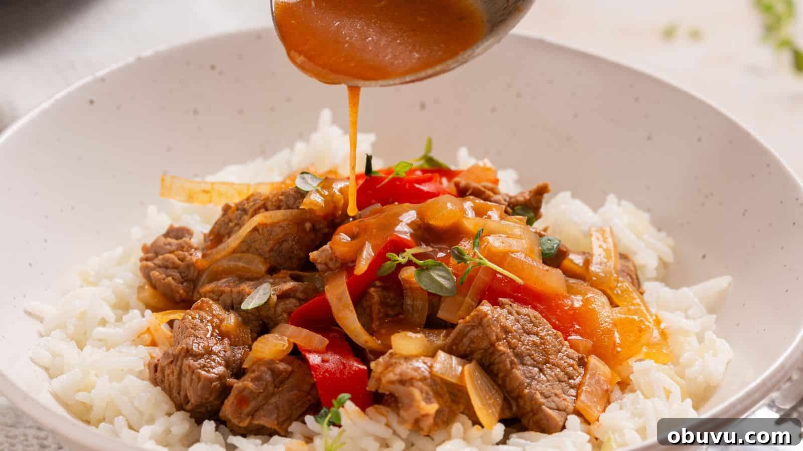 29 Delicious Low-Carb Meals That Aren’t Just Salad 2 Sauce being poured over a bowl of beef and bell pepper stir-fry served on white rice.
