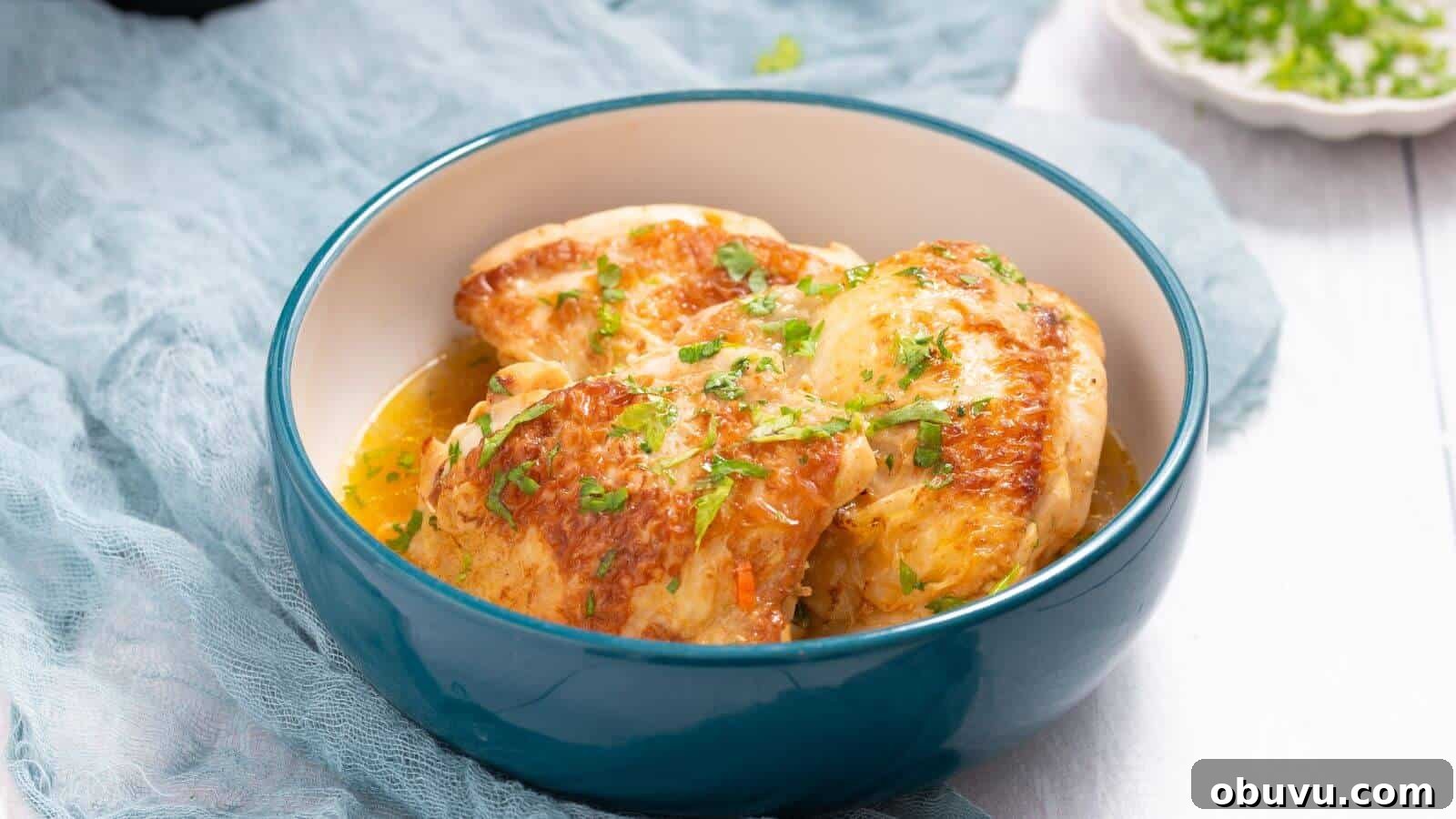 29 Delicious Low-Carb Meals That Aren’t Just Salad 27 A blue bowl of cooked chicken breasts garnished with chopped herbs on a light fabric backdrop.