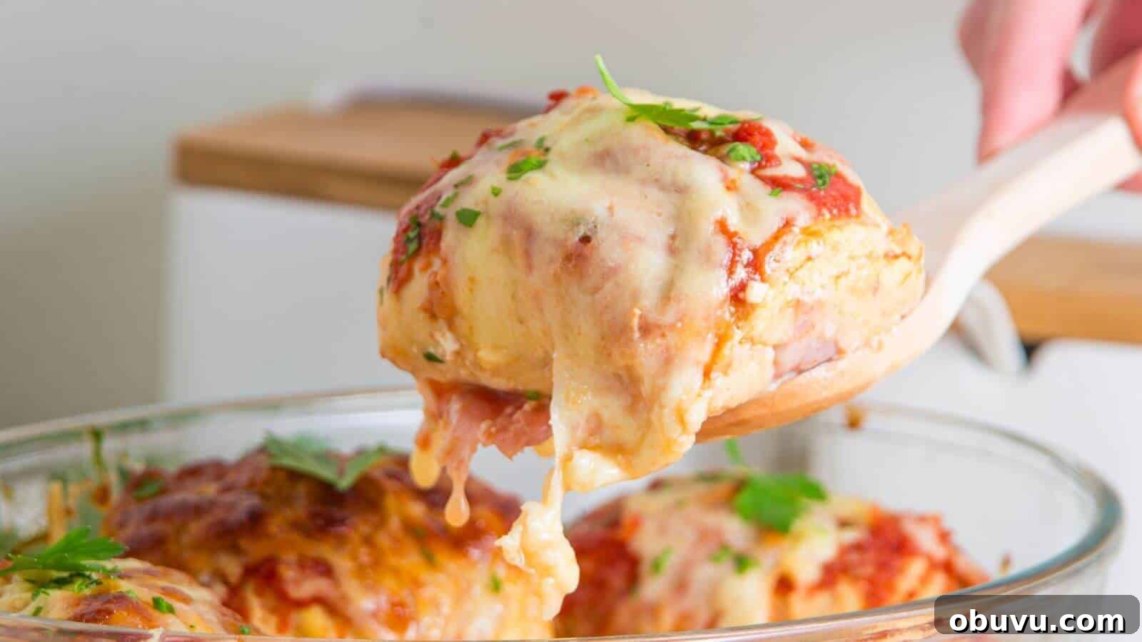 29 Delicious Low-Carb Meals That Aren’t Just Salad 4 A wooden spoon holds a piece of cheesy lasagna above a glass baking dish, garnished with fresh parsley.