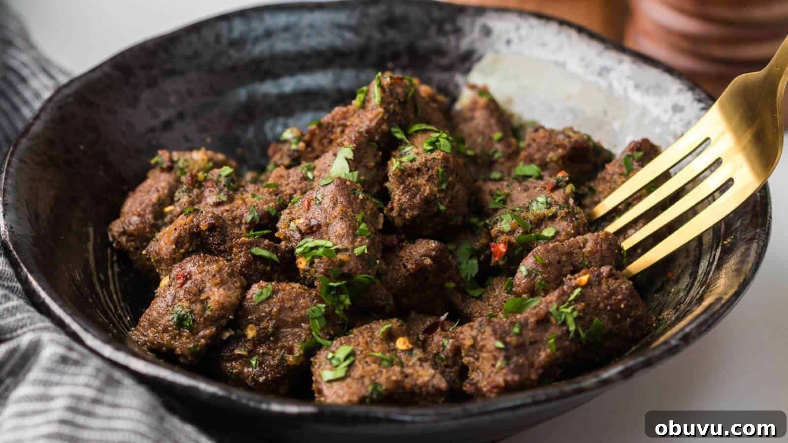 29 Delicious Low-Carb Meals That Aren’t Just Salad 6 A bowl of seasoned meat cubes garnished with chopped herbs, with a fork resting on the side.