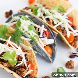 Savory Ground Turkey Tacos with Quick Homemade Seasoning 5 Three ground turkey tacos in a taco holder on a white platter.