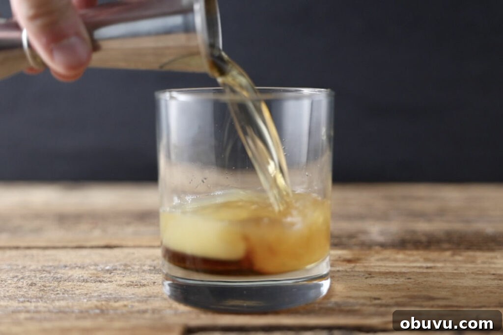 Maple Bourbon Smash Cocktail Recipe — Warm Autumn Whiskey Smash 5 Pouring bourbon in cocktail class.
