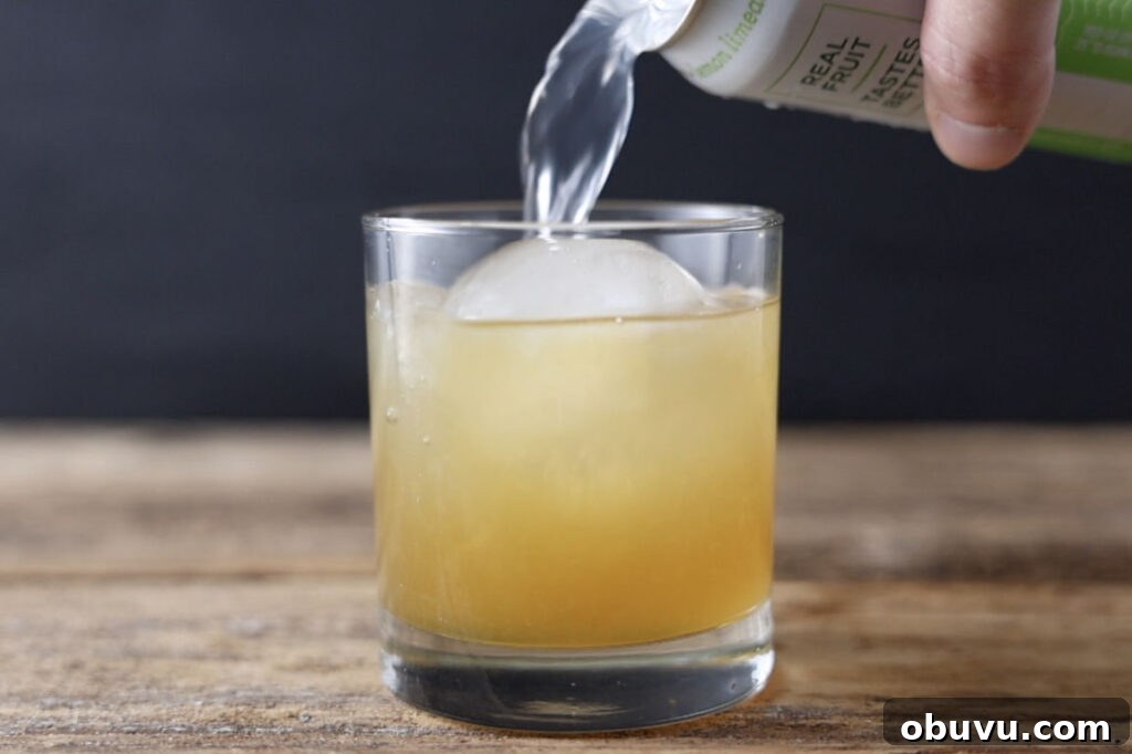 Maple Bourbon Smash Cocktail Recipe — Warm Autumn Whiskey Smash 8 Pouring seltzer water in cocktail.