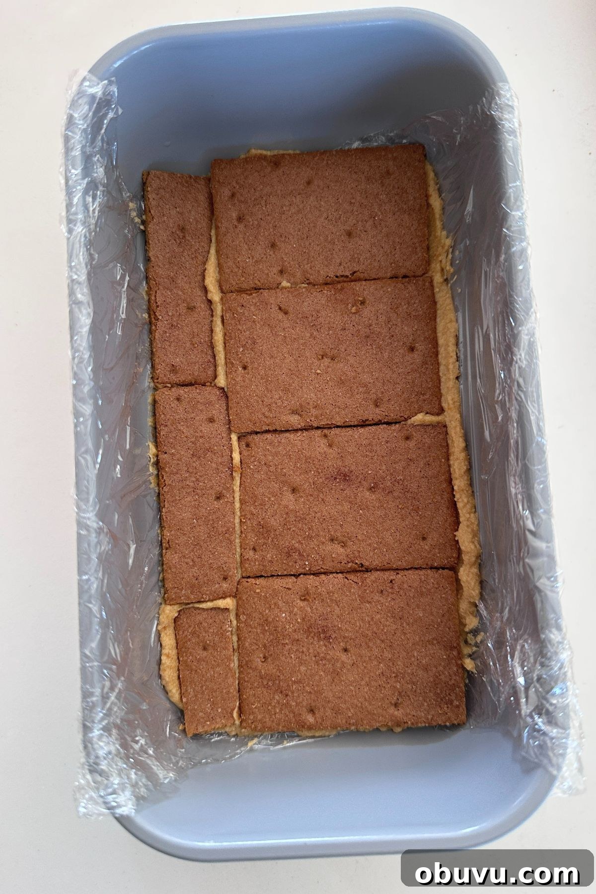 No-Bake Pumpkin Icebox Cake for Fall Desserts 5 Pumpkin cream in the bottom of plastic lined loaf pan topped with a single layer of graham crackers.