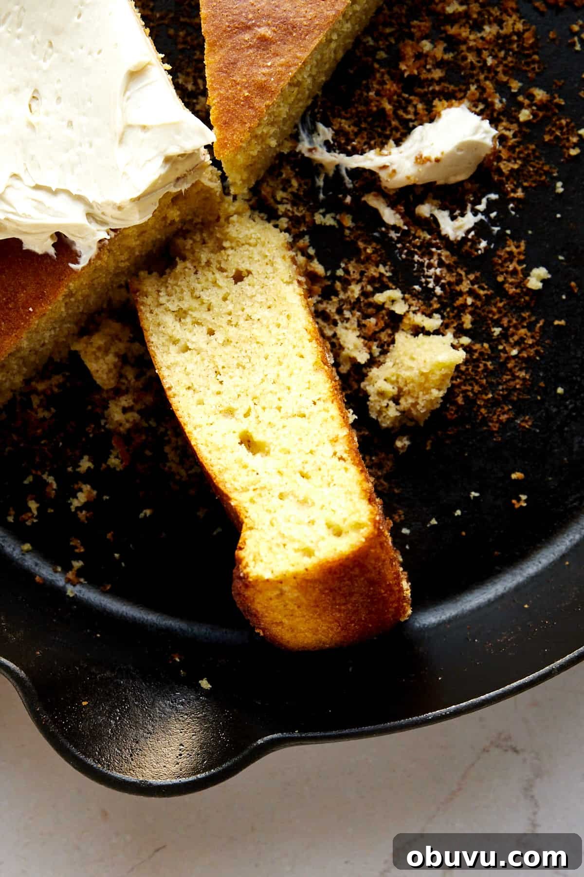 A piece of brown butter cornbread on its side in a skillet.