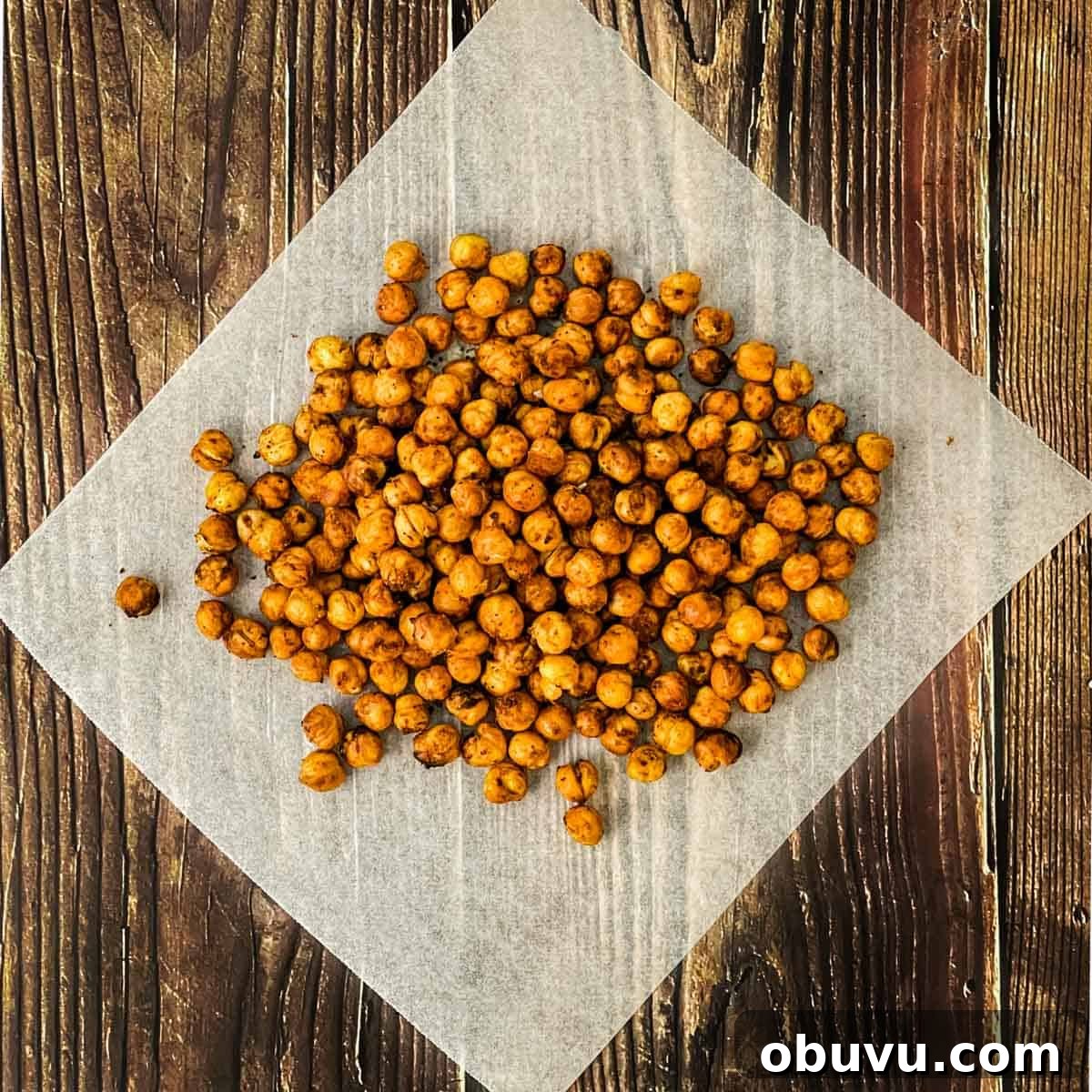 Crispy air fryer chickpeas on white paper on a wooden table.
