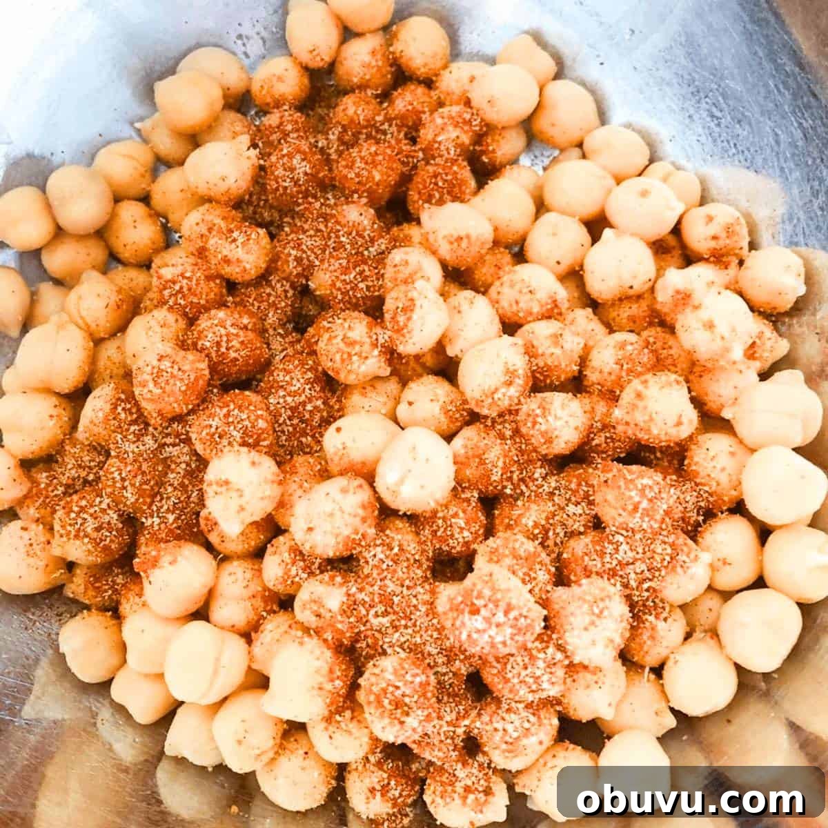 Seasoning and olive oil added to a large bowl with the chickpeas.