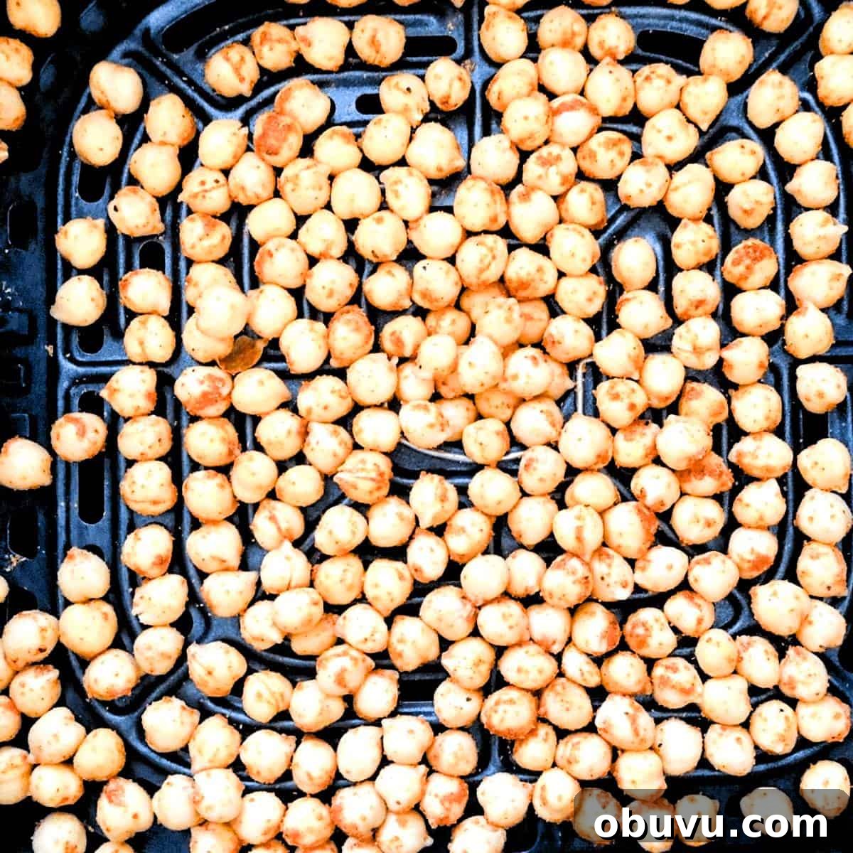 Seasoned chickpeas in a single layer in the air fryer basket.